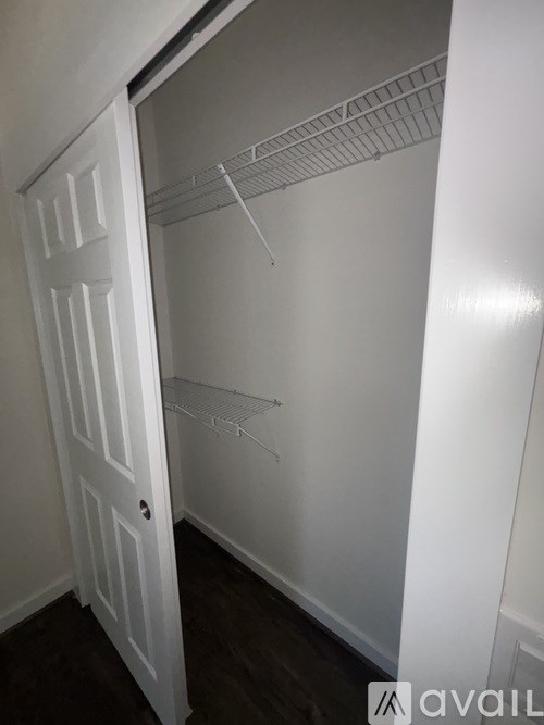 A white closet with a door open and shelves.