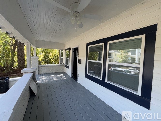 A porch with a bench and a window overlooking a street.