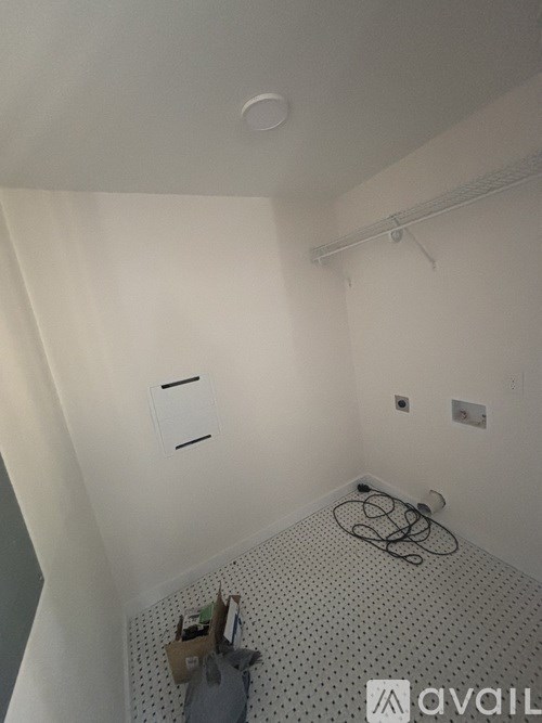 A bathroom with a white tiled floor and a white wall with a towel rack and a towel hanging on it.