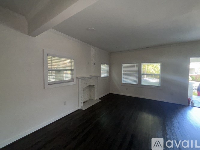 A room with a fireplace and two windows.