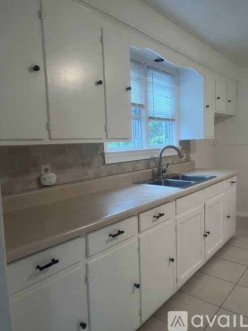 A kitchen with white cabinets and a window above the sink.