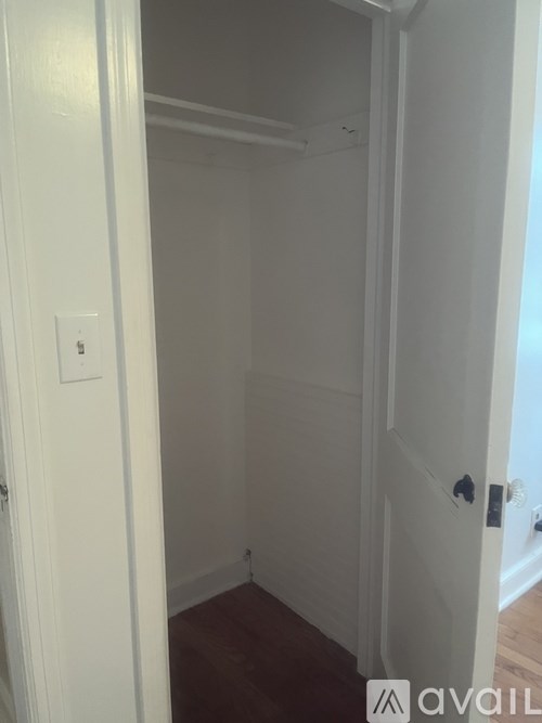 A white door with a handle and a light switch on the wall.