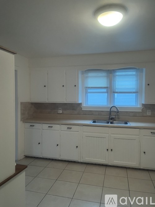A kitchen with white cabinets and a window above the sink.