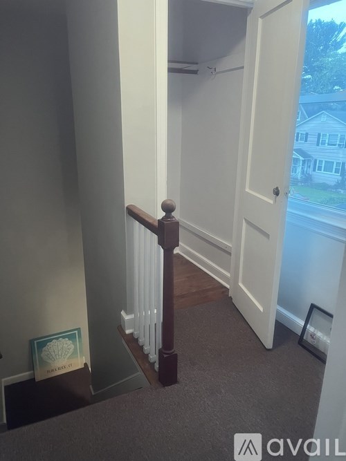 A hallway with a white door and a wooden staircase.