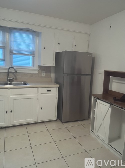 A kitchen with white cabinets and a stainless steel refrigerator.