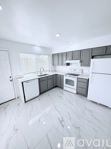 A modern kitchen with white appliances and a marble floor.
