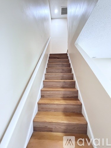 A flight of wooden stairs with white walls on either side.