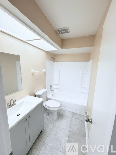 A bathroom with a toilet, sink, and mirror.