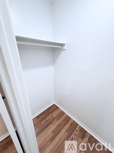 A white shelf in a corner of a room with wooden flooring.