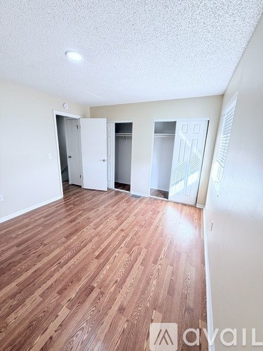 A room with wooden flooring and three white closets.