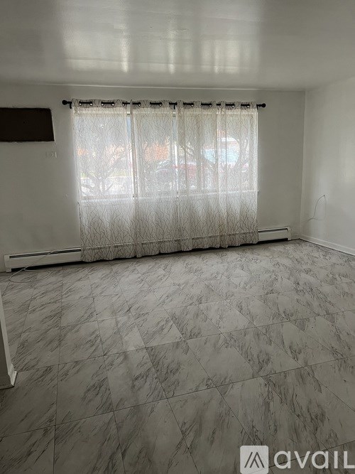 A room with a marble floor and a window with curtains.