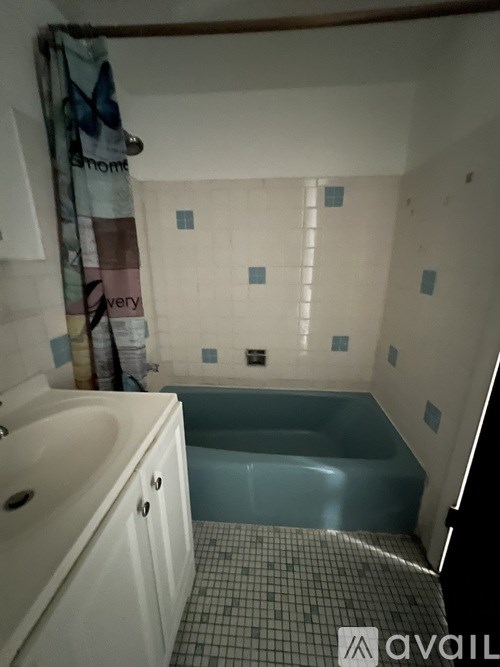 A bathroom with a tub, sink, and shower curtain.