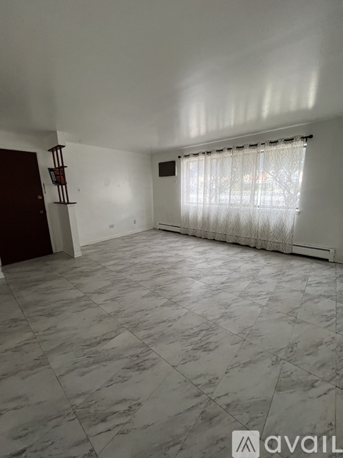 A room with a marble floor and a window with curtains.