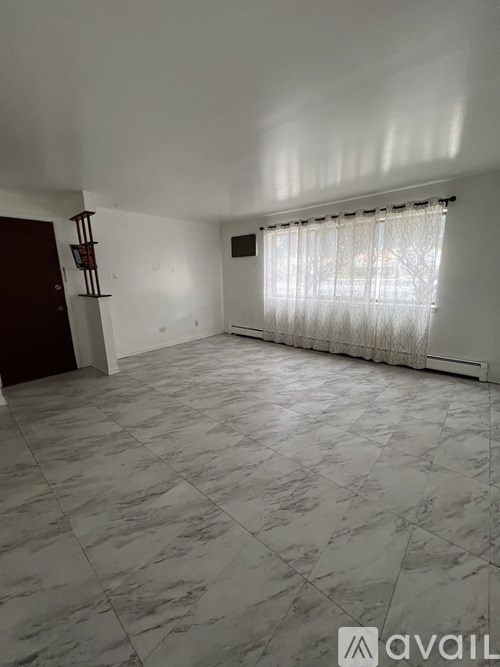 A room with a marble floor and a window with curtains.