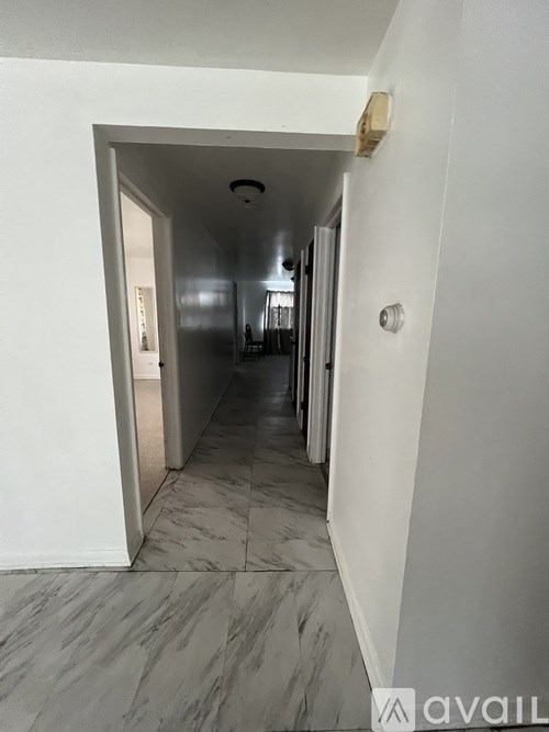 A hallway with a marble floor and white walls.