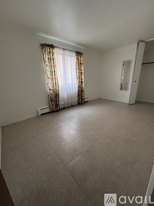 A room with a window covered by a curtain.