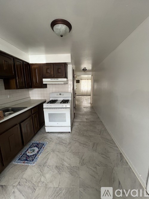 A kitchen with a white stove top oven and dark brown cabinets.