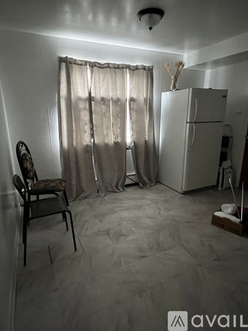 A room with a chair and a refrigerator.
