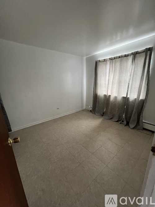 A room with a tiled floor and a window with curtains.