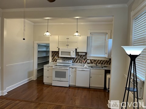 A kitchen with white cabinets and a black floor lamp.