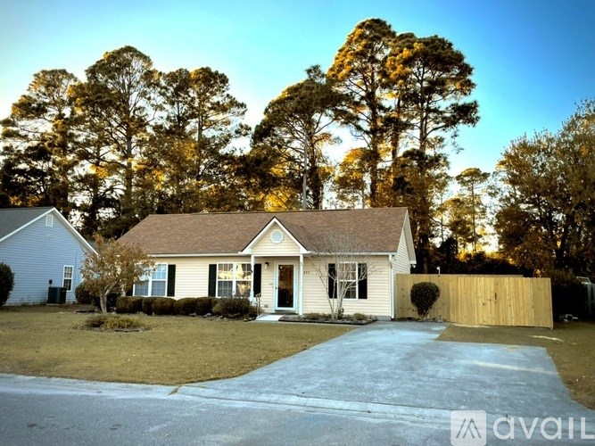 A house with a driveway and trees in the background.