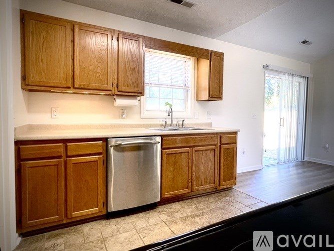 A kitchen with wooden cabinets and a stainless steel dishwasher.