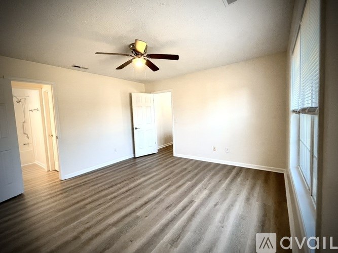 A room with a ceiling fan and wooden flooring.