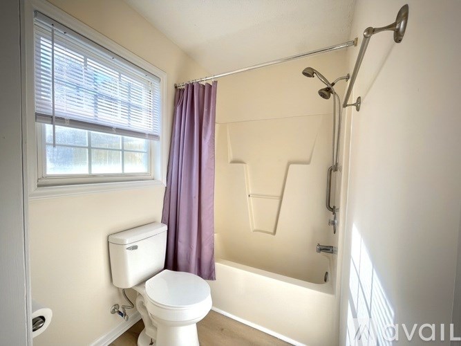 A white toilet sits next to a window in a bathroom.