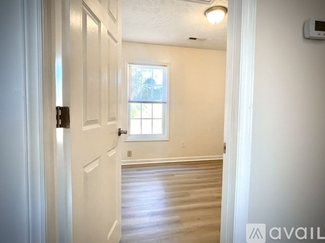 A hallway with a door on the left and a window on the right.