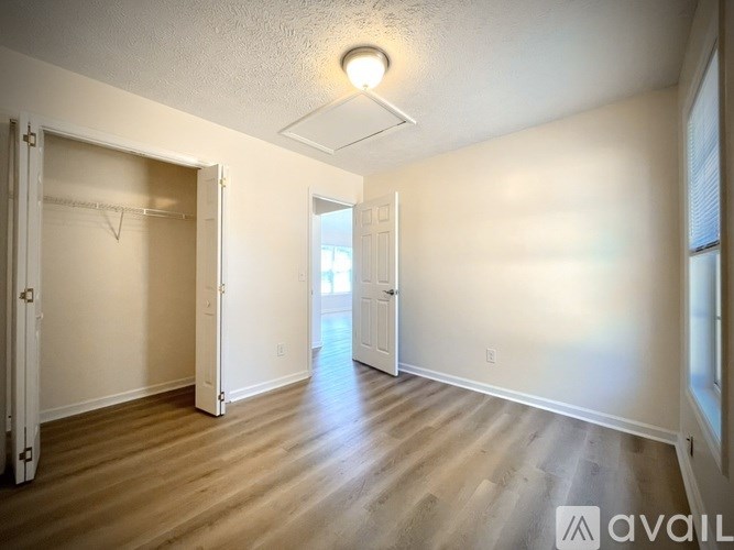A spacious room with wooden flooring and white walls.