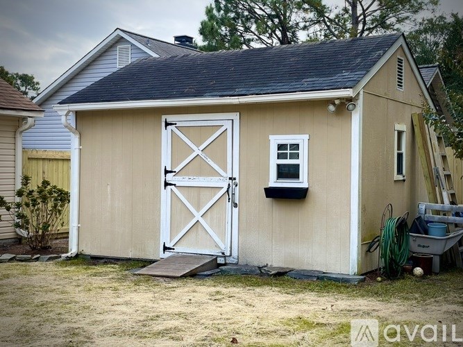 A shed with a white door and a small window is situated in a yard.