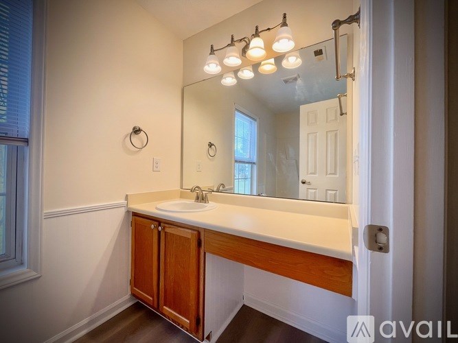 A bathroom with a white sink and a mirror with lights above it.