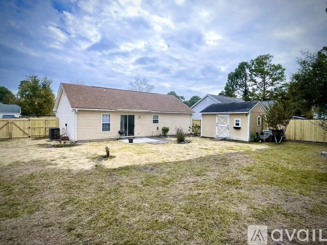 A white house with a brown roof is surrounded by a grassy area.