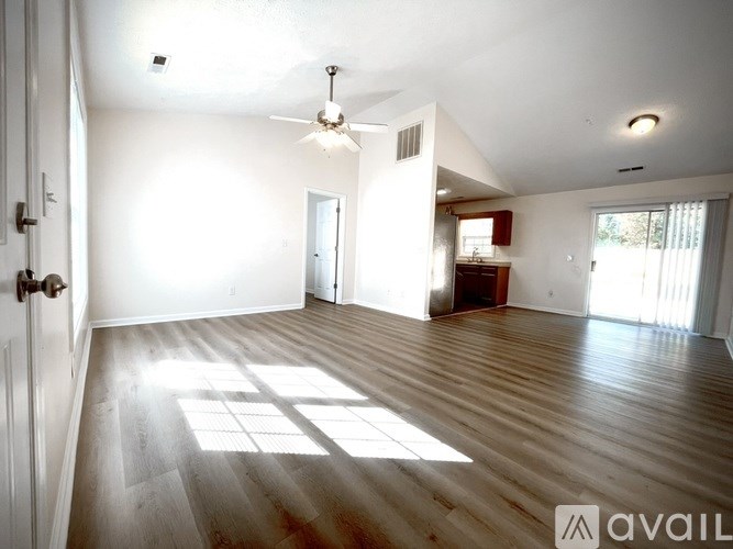 A spacious room with wooden floors and a ceiling fan.