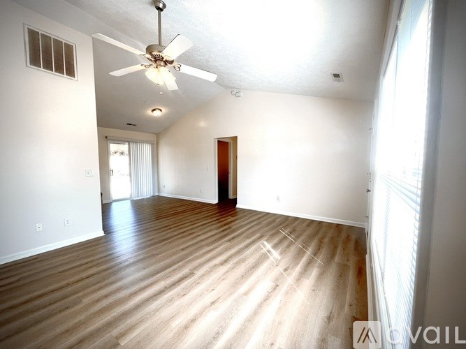 A room with a ceiling fan and wooden flooring.