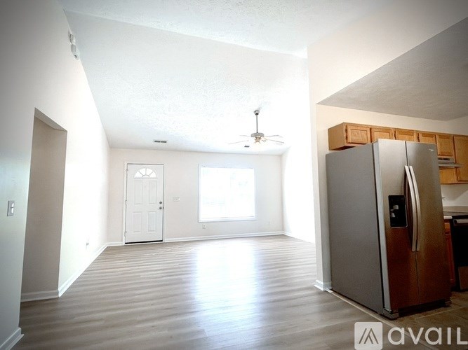 A kitchen area with a refrigerator, wooden cabinets, and a ceiling fan.