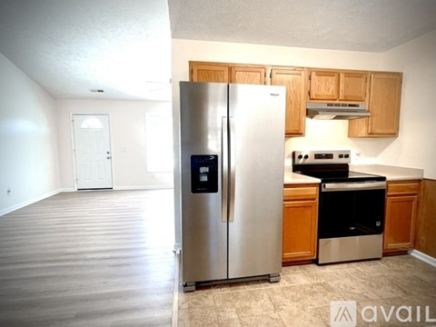 A kitchen with a stainless steel refrigerator and wooden cabinets.