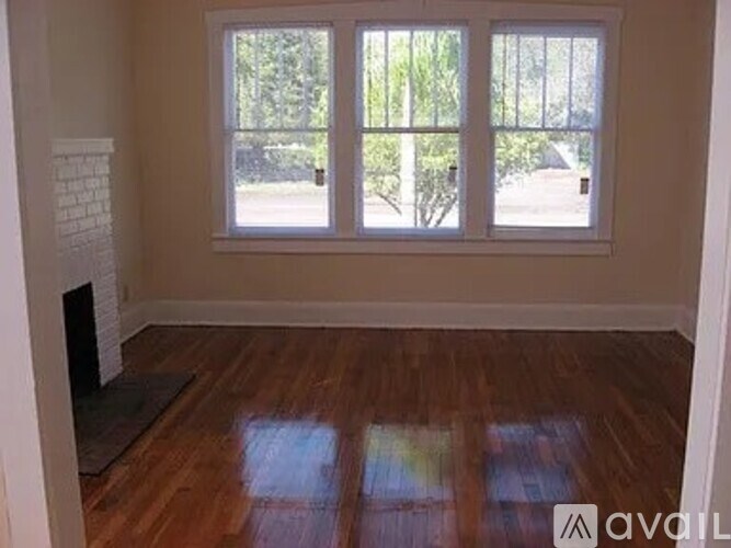 A room with a fireplace and a large window with a view of trees.