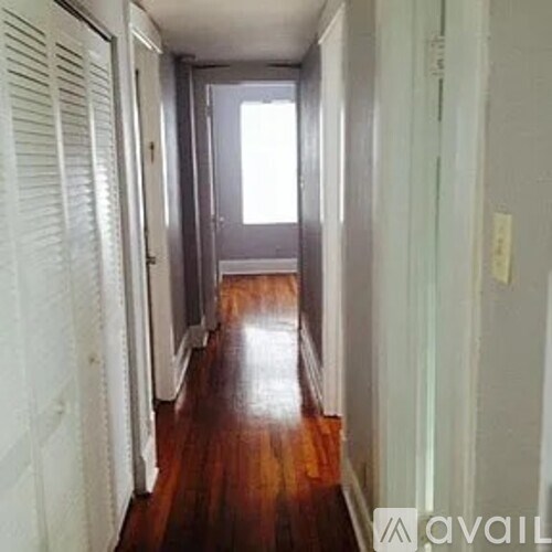 A long hallway with wood floors and white walls.
