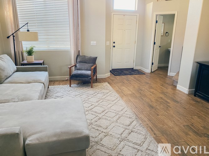 A living room with a grey couch, a chair, and a rug.