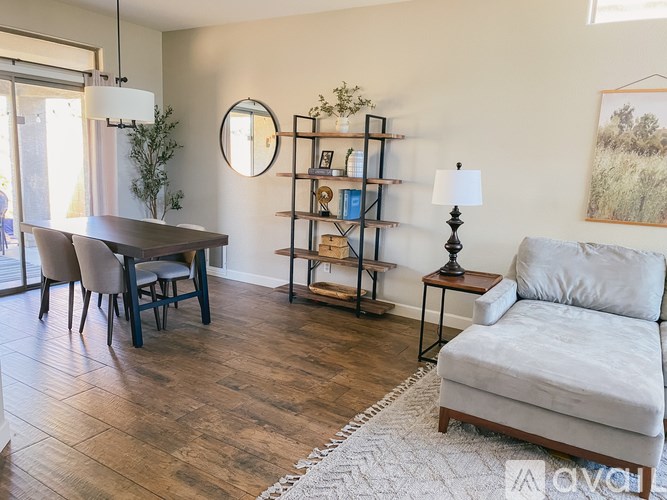 A living room with a grey couch, a wooden table, and a round mirror on the wall.