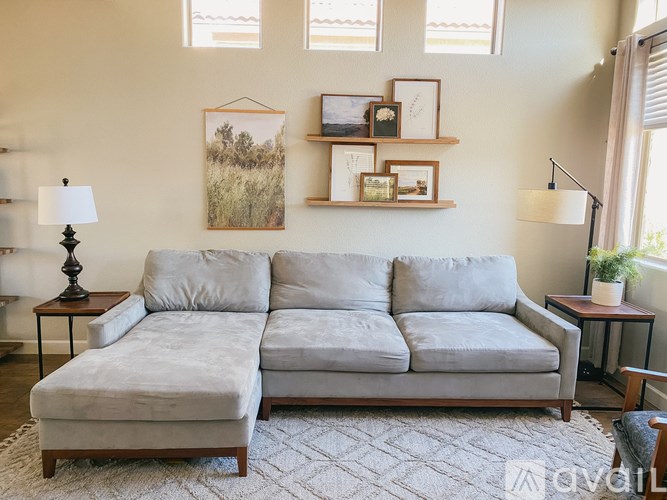 A living room with a grey couch and a painting on the wall.