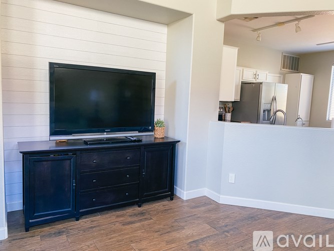 A black TV sits on a black cabinet in a room with white walls.