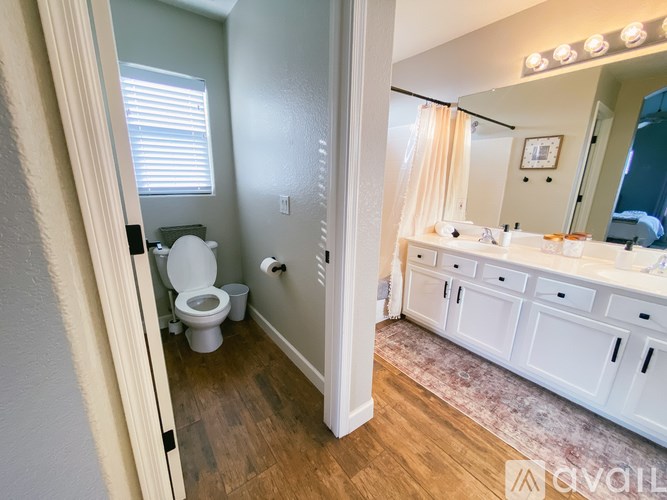 A bathroom with a toilet, sink, and mirror.