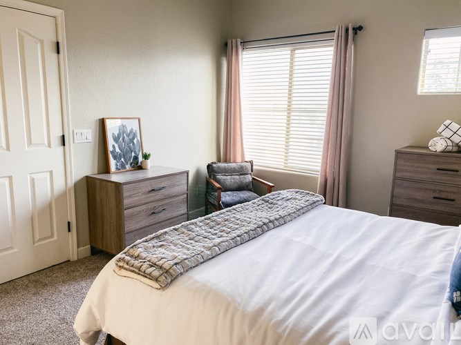 A bedroom with a large bed, a chair, and a dresser.