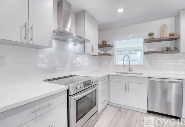 A modern kitchen with white cabinets and stainless steel appliances.