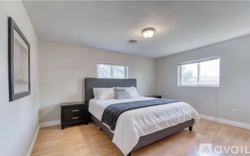 A bedroom with a bed, nightstand, and a painting on the wall.
