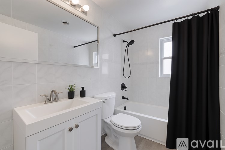 A bathroom with a white sink, toilet, and black shower curtain.
