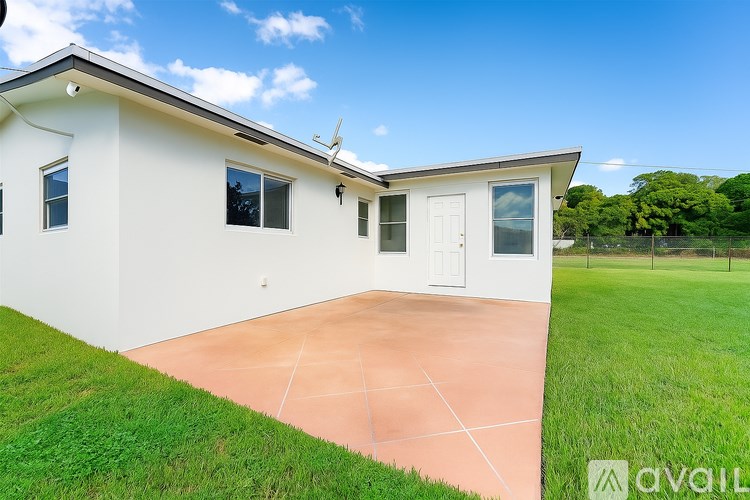 A white house with a brown roof and a white door is surrounded by a green lawn.