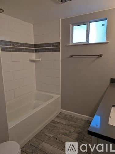 A bathroom with a white tub and tiled walls.